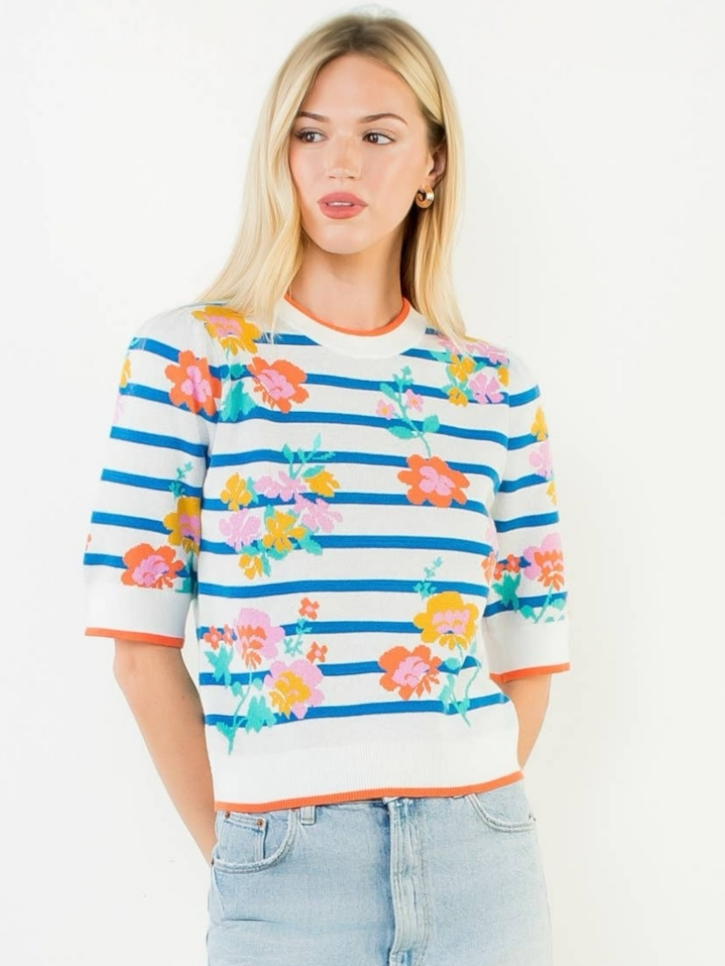 Woman wearing a colorful striped sweater with floral patterns on a white background