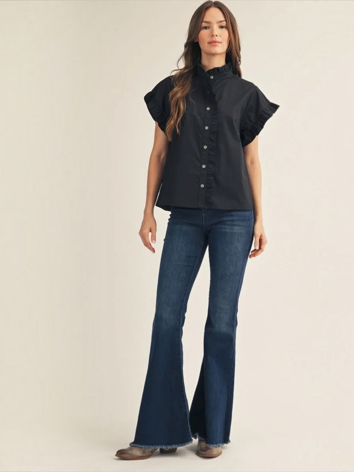 Full-length view of woman wearing Jodifl black ruffle collar button-down top with jeans