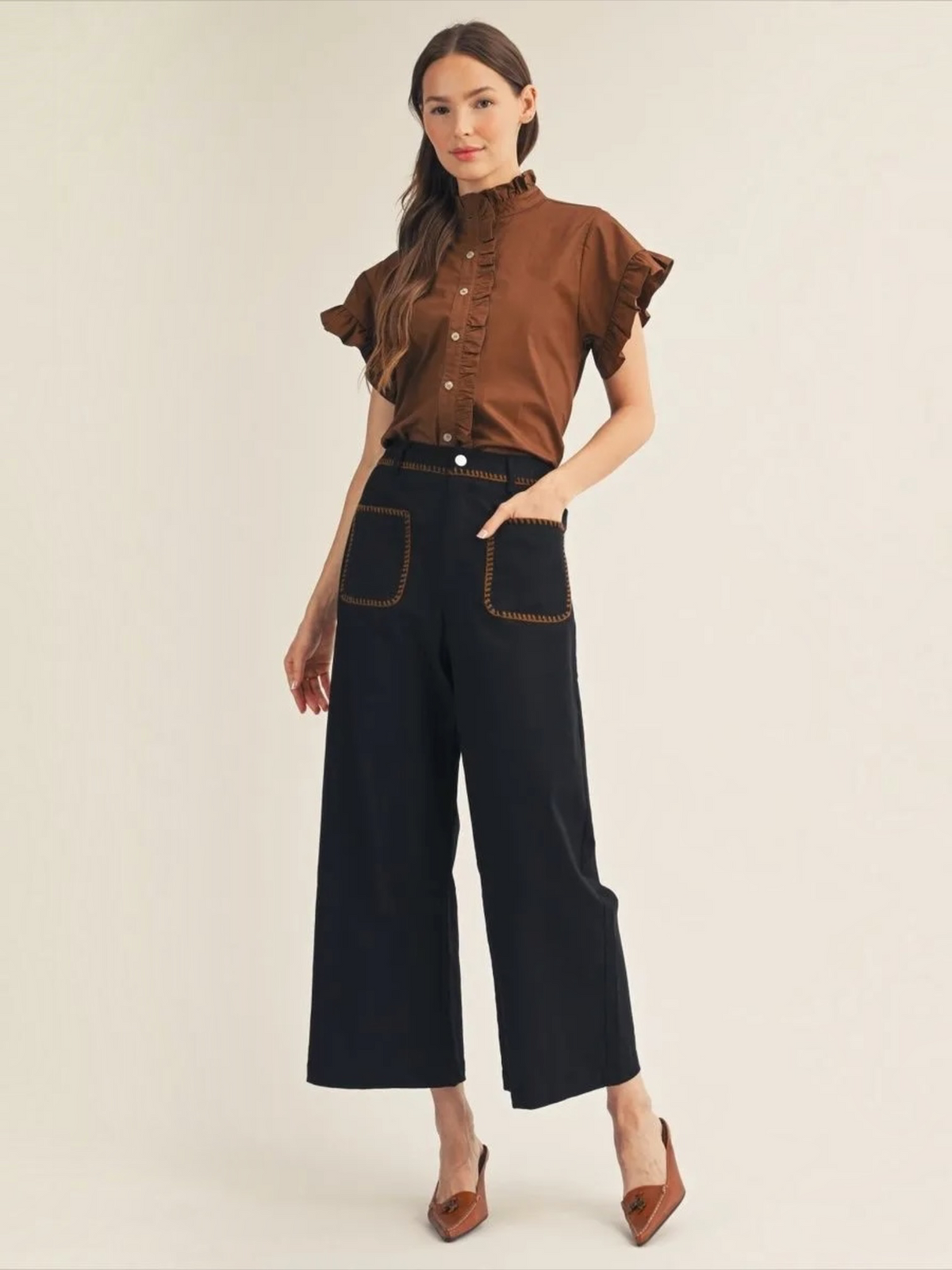 Woman wearing a Jodifl brown ruffle collar button-down cotton top with black pants