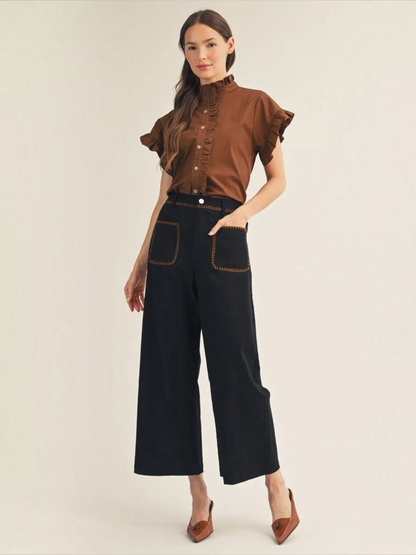 Woman wearing a Jodifl brown ruffle collar button-down cotton top with black pants